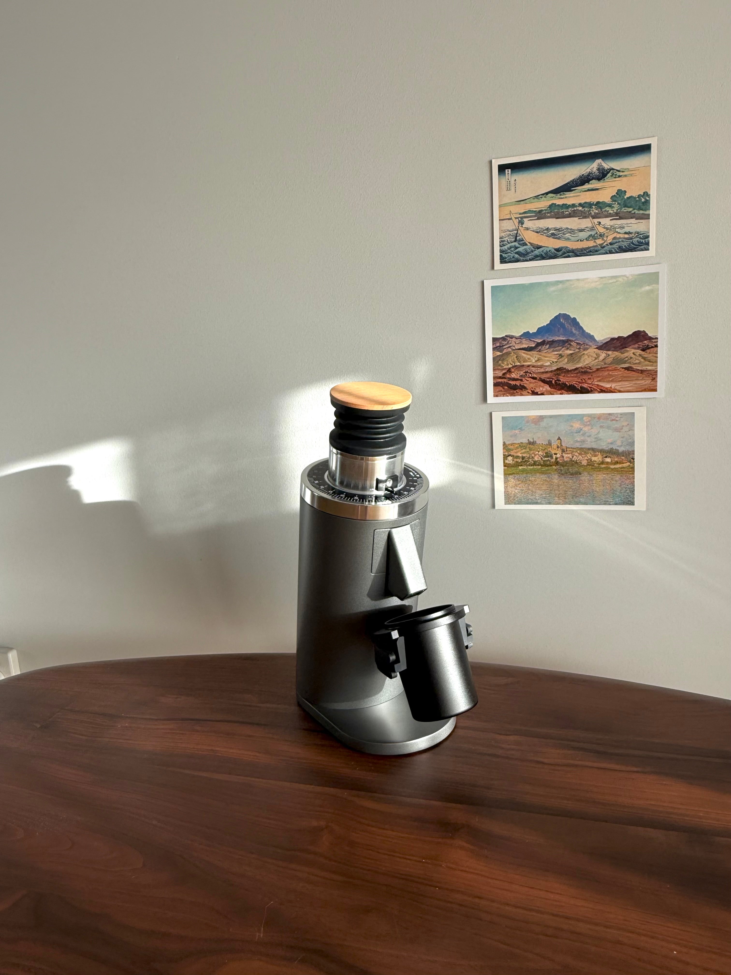 Grey DF54 Coffee Grinder with black metal dosing cup on wooden table - Grind Logic