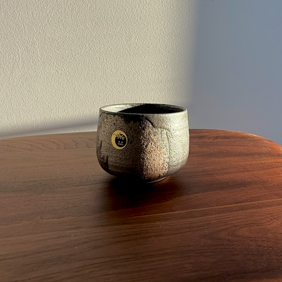 Ceramic cup with a gold emblem on a wooden surface