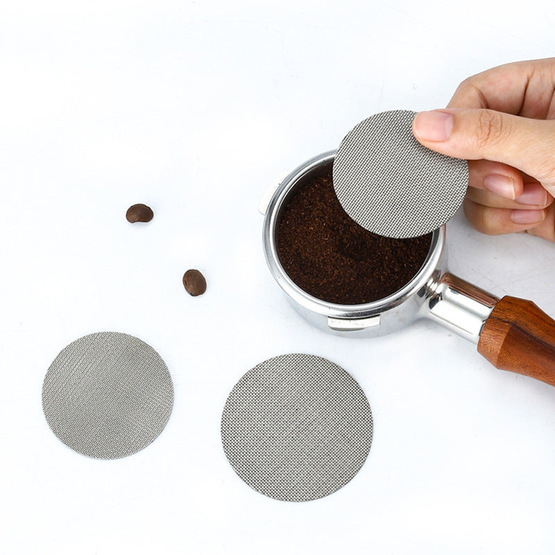 Hand placing a fine mesh espresso puck screen over ground coffee in a portafilter basket - Grind Logic