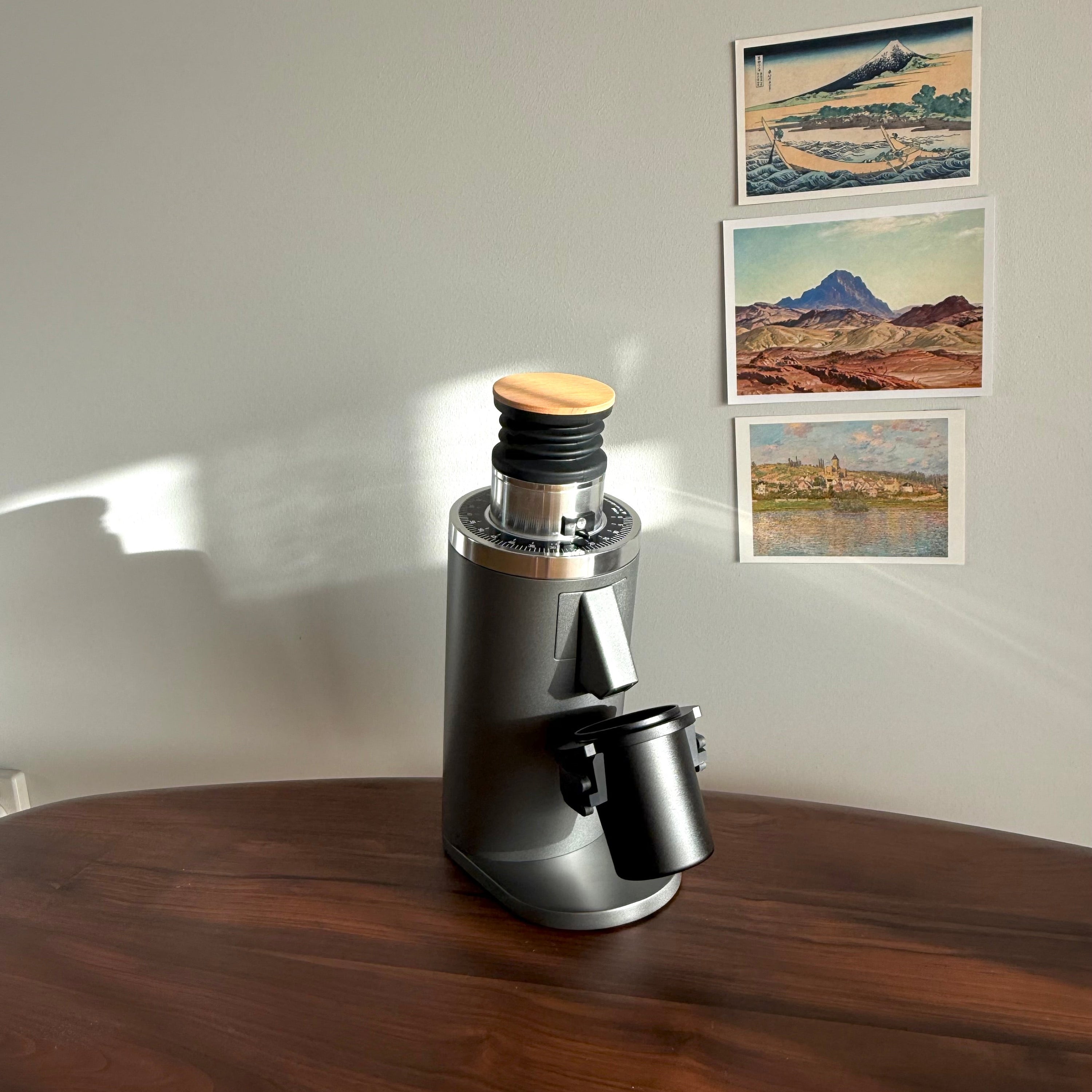 Grey DF54 Coffee Grinder with black metal dosing cup on wooden table - Grind Logic