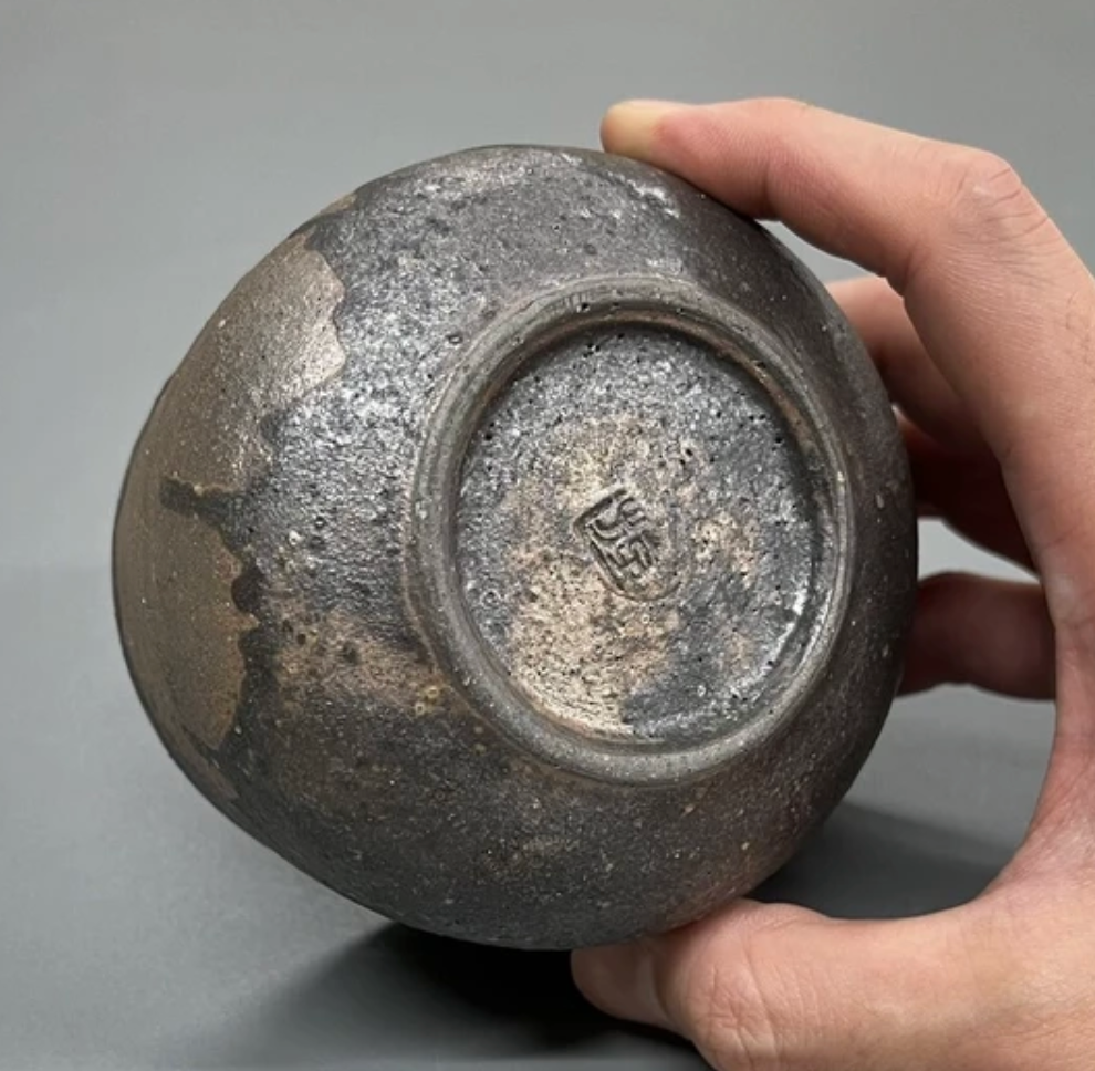Hand holding a textured ceramic cup against a gray background