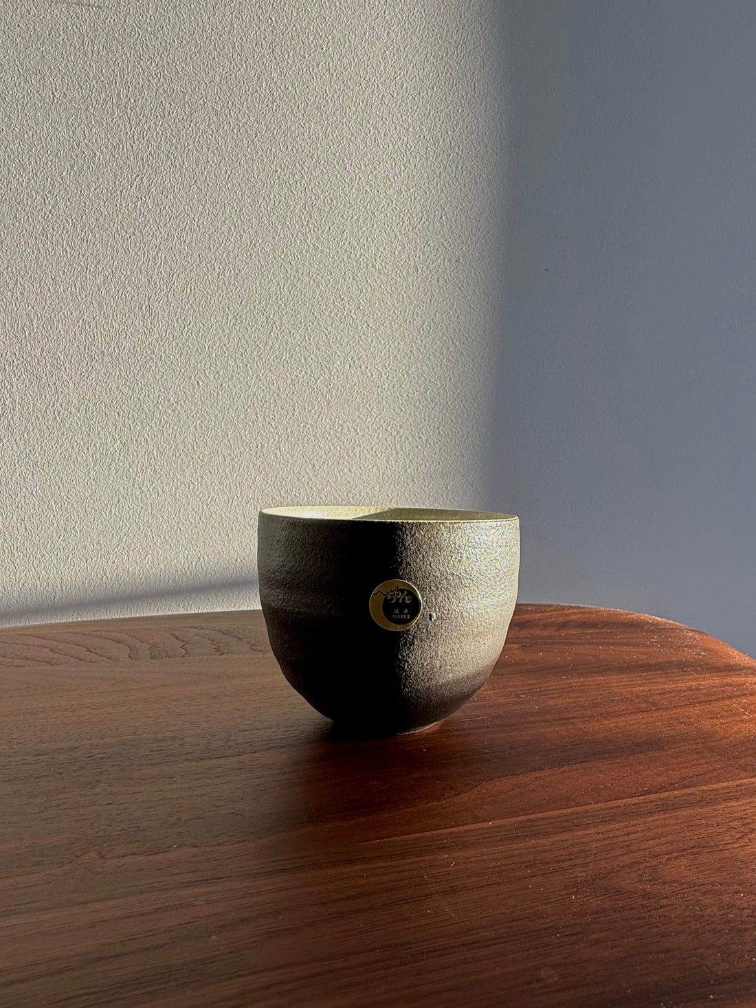 Ceramic bowl with a textured surface on a wooden table against a neutral wall.