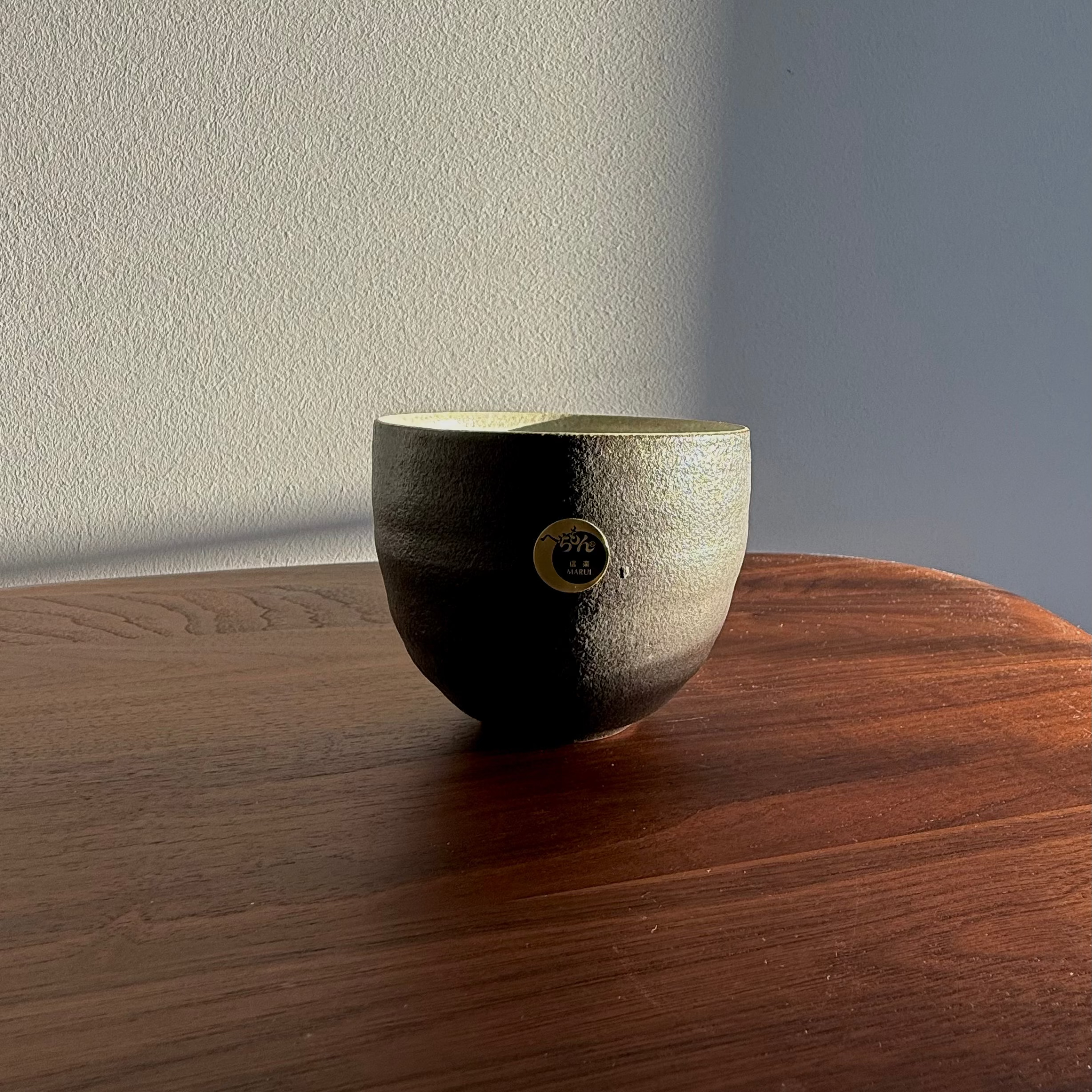 Ceramic bowl with a textured surface on a wooden table against a neutral wall.
