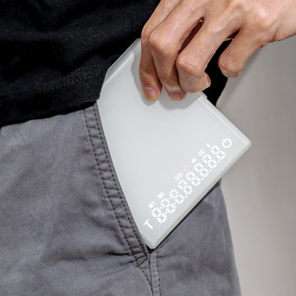 White Grind Logic Mini Espresso Scale being carried in a pocket, showing its compact portable size